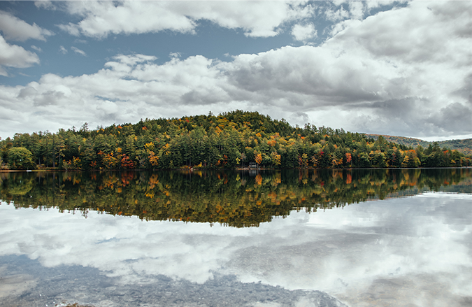 Photo of lake in Maine with fall foliage and clouds