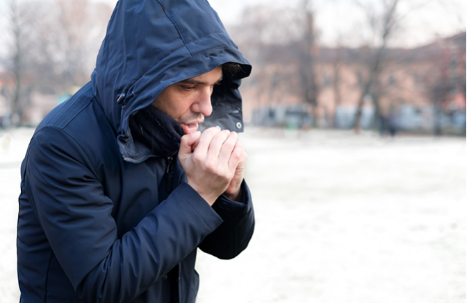 Man in winter coat in cold weather warming up his hands