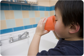 a boy drinks water from kitchen sink